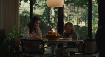 Movie still from “The Nest” (2020), directed by Sean Durkin – Two people sitting at a table with a bowl of fruit; Medium shot, Over the shoulder angle