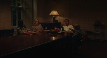 Movie still from “The Nest” (2020), directed by Sean Durkin – A group of people sitting around a table eating food; Wide shot, High angle