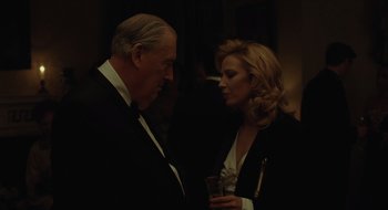 Movie still from “The Nest” (2020), directed by Sean Durkin – A man and a woman standing next to each other holding a glass; Medium shot, Low angle