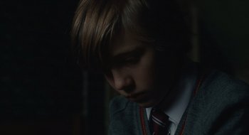 Movie still from “The Nest” (2020), directed by Sean Durkin – A young man in a sweater and a tie; Close Up shot, Over the shoulder angle