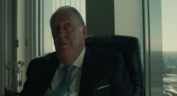 Movie still from “The Nest” (2020), directed by Sean Durkin – An older man wearing a suit and tie sitting in an office chair; Close Up shot, Over the shoulder angle