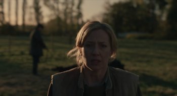 Movie still from “The Nest” (2020), directed by Sean Durkin – A woman is standing in a field looking at the camera; Medium shot, Over the shoulder angle