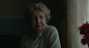 Movie still from “The Nest” (2020), directed by Sean Durkin – An older woman is posing for a picture; Close Up shot, Over the shoulder angle