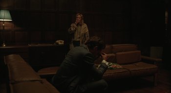 Movie still from “The Nest” (2020), directed by Sean Durkin – A man and a woman sitting on a couch in front of a phone; Medium shot, High angle