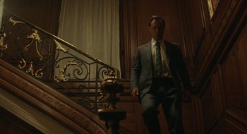 Movie still from “The Nest” (2020), directed by Sean Durkin – A man in a suit and tie walking down a staircase; Wide shot, Low angle