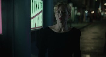 Movie still from “The Nest” (2020), directed by Sean Durkin – A woman standing in front of a lit up sign; Medium shot, Over the shoulder angle