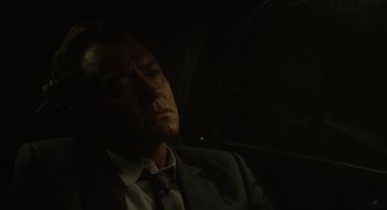 Movie still from “The Nest” (2020), directed by Sean Durkin – A man wearing a suit and tie sitting in the back of a car; Close Up shot, Low angle