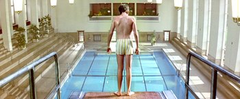 Movie still from “The NeverEnding Story II: The Next Chapter” (1990), directed by George Miller – A man standing in front of a swimming pool; Wide shot, Overhead angle