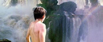 Movie still from “The NeverEnding Story II: The Next Chapter” (1990), directed by George Miller – A man standing in front of a large waterfall; Wide shot, Low angle