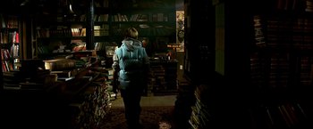 Movie still from “The NeverEnding Story II: The Next Chapter” (1990), directed by George Miller – A person in a room filled with lots of books; Medium shot, High angle