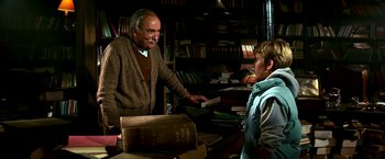 Movie still from “The NeverEnding Story II: The Next Chapter” (1990), directed by George Miller – An older man and a young boy in a book store; Medium shot, Low angle