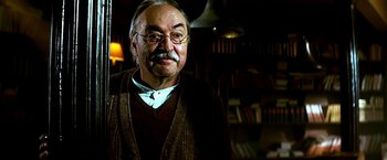 Movie still from “The NeverEnding Story II: The Next Chapter” (1990), directed by George Miller – An older man wearing glasses and a brown sweater; Close Up shot, Low angle