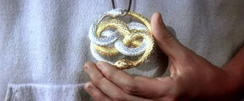 Movie still from “The NeverEnding Story II: The Next Chapter” (1990), directed by George Miller – A person holding a gold and silver snake necklace; Extreme Close Up shot, Overhead angle