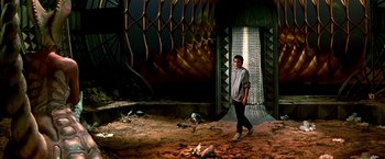 Movie still from “The NeverEnding Story II: The Next Chapter” (1990), directed by George Miller – A man standing in front of an open door; Wide shot, Low angle