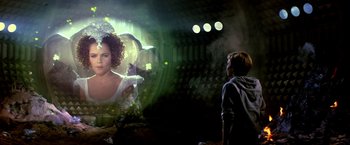 Movie still from “The NeverEnding Story II: The Next Chapter” (1990), directed by George Miller – A man and a woman in a room with lights; Medium shot, Over the shoulder angle