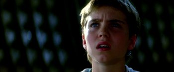 Movie still from “The NeverEnding Story II: The Next Chapter” (1990), directed by George Miller – A young boy with blue eyes looking up at the sky; Close Up shot, Low angle