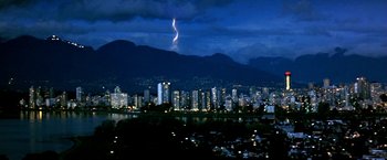 Movie still from “The NeverEnding Story II: The Next Chapter” (1990), directed by George Miller – A city skyline at night under a cloudy sky; Extreme Wide shot, High angle