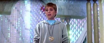 Movie still from “The NeverEnding Story II: The Next Chapter” (1990), directed by George Miller – A young boy wearing a necklace and a hoodie; Close Up shot, Low angle