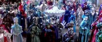 Movie still from “The NeverEnding Story II: The Next Chapter” (1990), directed by George Miller – A group of people dressed up in costumes and masks; Wide shot, High angle