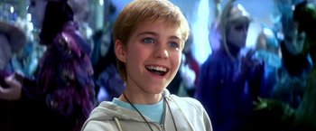 Movie still from “The NeverEnding Story II: The Next Chapter” (1990), directed by George Miller – A young boy with a blue eyes and a white shirt; Close Up shot, Low angle