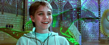 Movie still from “The NeverEnding Story II: The Next Chapter” (1990), directed by George Miller – A young boy smiling in front of an image of a staircase; Close Up shot, Low angle