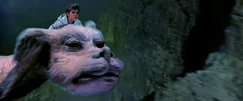 Movie still from “The NeverEnding Story II: The Next Chapter” (1990), directed by George Miller – A man riding on the back of an animal head; Close Up shot, High angle