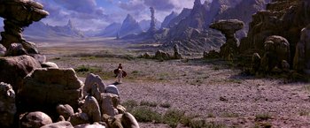 Movie still from “The NeverEnding Story II: The Next Chapter” (1990), directed by George Miller – A man walking across a dirt road in the middle of the desert; Extreme Wide shot, High angle