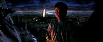 Movie still from “The NeverEnding Story II: The Next Chapter” (1990), directed by George Miller – A young man standing in front of a rocket; Medium shot, High angle