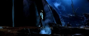 Movie still from “The NeverEnding Story II: The Next Chapter” (1990), directed by George Miller – A man standing on top of a mountain near a waterfall; Wide shot, High angle
