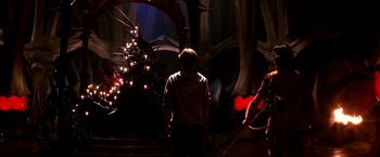 Movie still from “The NeverEnding Story II: The Next Chapter” (1990), directed by George Miller – A man standing next to another man in a dark room; Wide shot, Over the shoulder angle