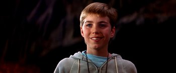 Movie still from “The NeverEnding Story II: The Next Chapter” (1990), directed by George Miller – A young man smiling for the camera; Close Up shot, Low angle