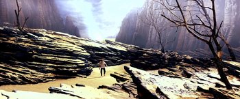 Movie still from “The NeverEnding Story II: The Next Chapter” (1990), directed by George Miller – A man standing on top of a hill near some rocks; Extreme Wide shot, High angle