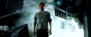 Movie still from “The NeverEnding Story II: The Next Chapter” (1990), directed by George Miller – A young man standing in front of a smoke filled building; Medium shot, Low angle