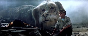Movie still from “The NeverEnding Story II: The Next Chapter” (1990), directed by George Miller – An image of a creature in the background; Medium shot, Over the shoulder angle