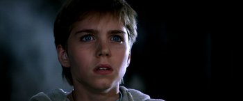 Movie still from “The NeverEnding Story II: The Next Chapter” (1990), directed by George Miller – A young boy with blue eyes stares into the distance; Close Up shot, Low angle