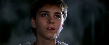 Movie still from “The NeverEnding Story II: The Next Chapter” (1990), directed by George Miller – A young boy with blue eyes looking upward; Close Up shot, Low angle
