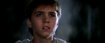 Movie still from “The NeverEnding Story II: The Next Chapter” (1990), directed by George Miller – A young boy with blue eyes stares into the distance; Close Up shot, Low angle