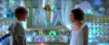 Movie still from “The NeverEnding Story II: The Next Chapter” (1990), directed by George Miller – A woman standing in front of a stage with a dancer in the background; Wide shot, Low angle