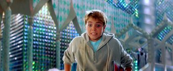 Movie still from “The NeverEnding Story II: The Next Chapter” (1990), directed by George Miller – A young man in a gray hoodie smiling for the camera; Medium shot, Low angle