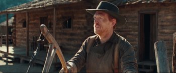 Movie still from “Hostiles” (2017), directed by Scott Cooper – A man in a hat holding a wooden stick; Medium shot, Over the shoulder angle