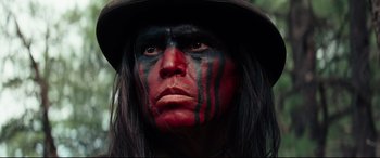 Movie still from “Hostiles” (2017), directed by Scott Cooper – A man with red and black face paint and a hat; Close Up shot, Low angle