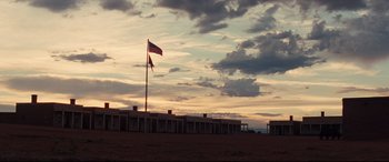 Movie still from “Hostiles” (2017), directed by Scott Cooper – A flag is flying in front of a sunset; Extreme Wide shot, Low angle