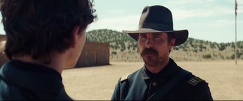 Movie still from “Hostiles” (2017), directed by Scott Cooper – A man wearing a hat and a uniform talking to another man; Close Up shot, Over the shoulder angle