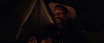Movie still from “Hostiles” (2017), directed by Scott Cooper – A man with a hat is sitting in the dark; Close Up shot, Low angle