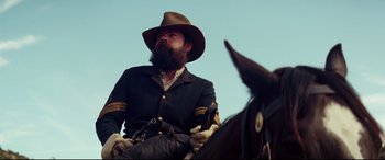 Movie still from “Hostiles” (2017), directed by Scott Cooper – A man with a long beard sitting on top of a horse; Close Up shot, Low angle