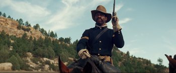 Movie still from “Hostiles” (2017), directed by Scott Cooper – A man on a horse holding a gun in his hand; Medium shot, Low angle