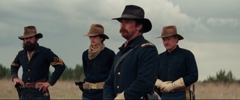 Movie still from “Hostiles” (2017), directed by Scott Cooper – A group of men standing next to each other in a field; Medium shot, Low angle