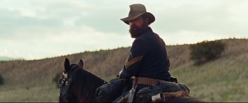 Movie still from “Hostiles” (2017), directed by Scott Cooper – A man with a beard is sitting on a horse; Medium shot, Low angle