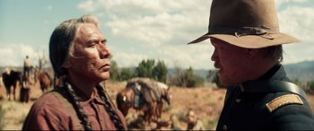 Movie still from “Hostiles” (2017), directed by Scott Cooper – Two men talking in a field with horses in the background; Medium shot, Over the shoulder angle