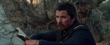 Movie still from “Hostiles” (2017), directed by Scott Cooper – A person sitting in a field; Close Up shot, Over the shoulder angle